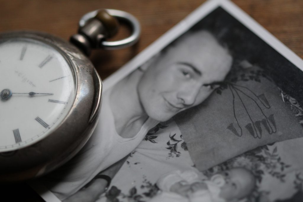 un orologio da taschino appoggia sopra una fotografia di un uomo con un bimbo piccolo