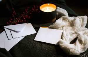 buste e lettere in bianco davanti a una candela accesa