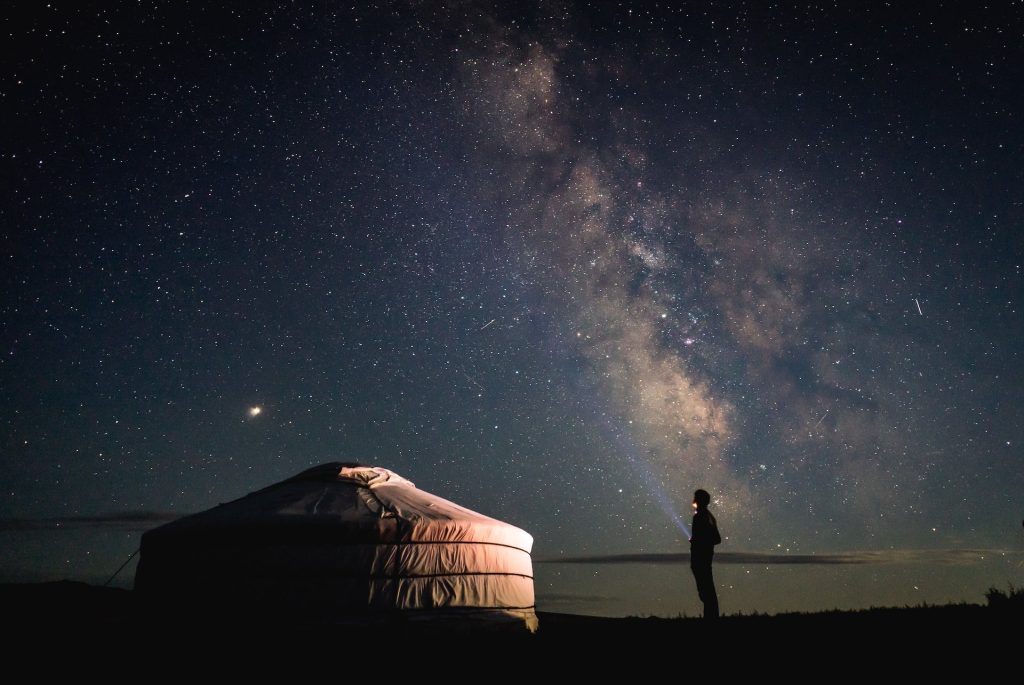 uomo guarda il cielo notturno di fronte a una grande tenda bianca