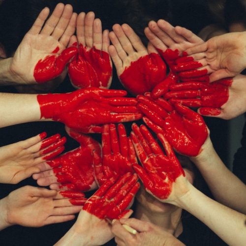 tante mani colorate di rosso si uniscono a formare un grande cuore