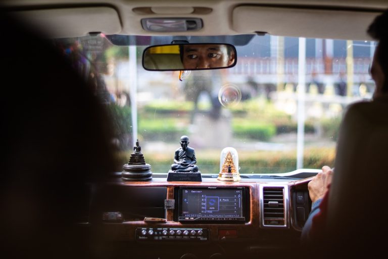 visione dell'abitacolo di un'auto con una statua di Buddha sul cruscotto che invita a guidare con la presenza che salva la vita