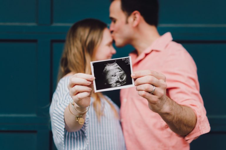 donna e uomo si baciano con in mano una ecografia di un feto. Il papà ha una grande importanza anche se indiretta nella genesi della prima ferita