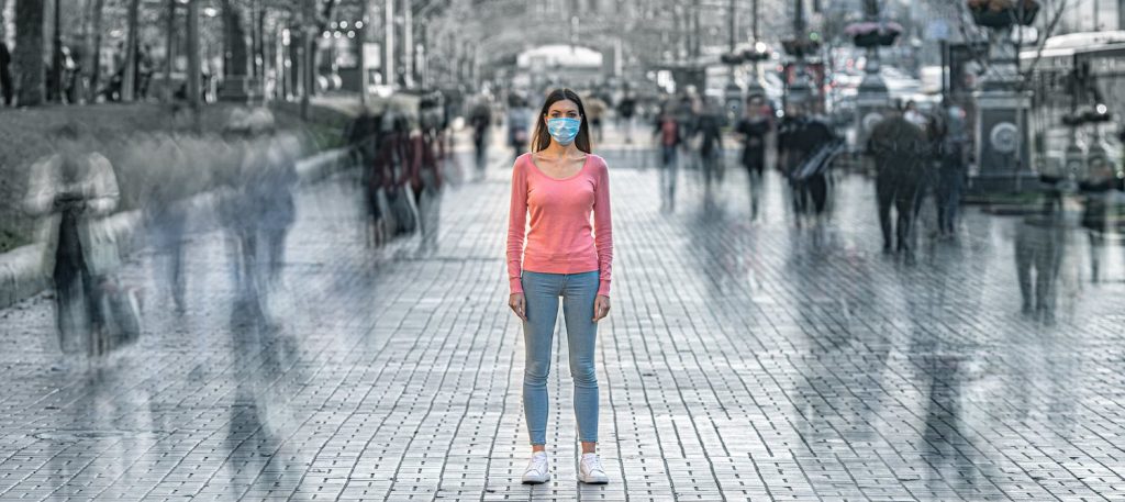 donna in piedi con mascherina in una strada pubblica