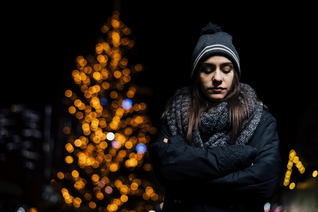 Donna a occhi chiusi da le spalle all'albero di natale: perché si odia il Natale? ci sono molti motivi legati all'infanzia