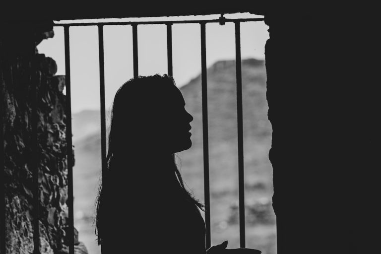 sagoma di donna dietro delle sbarre di una prigione: per cambiare lavoro e vita è necessario uscire dalle proprie prigioni mentali