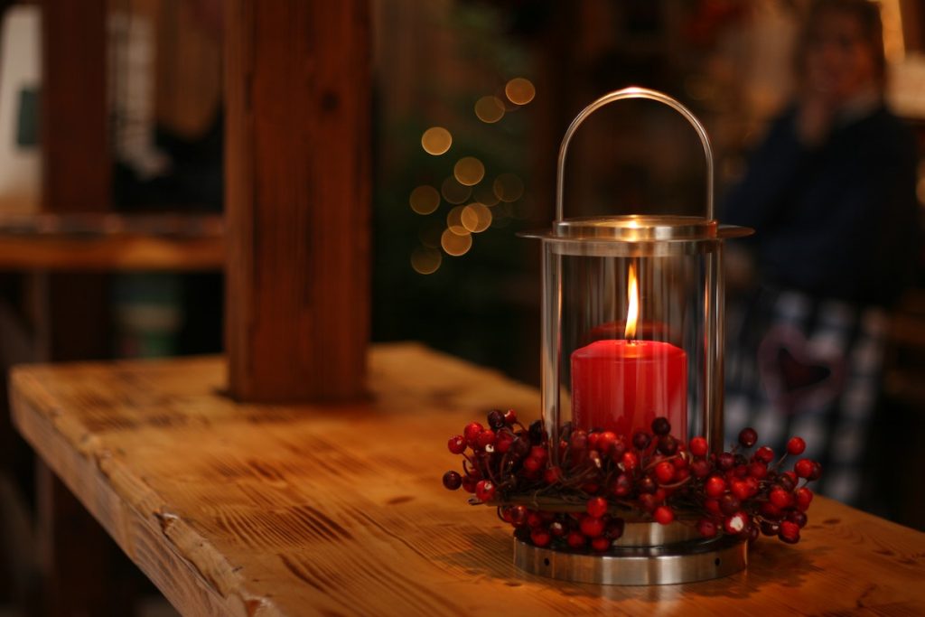 candela rossa accesa su un tavolo di legno con vischio