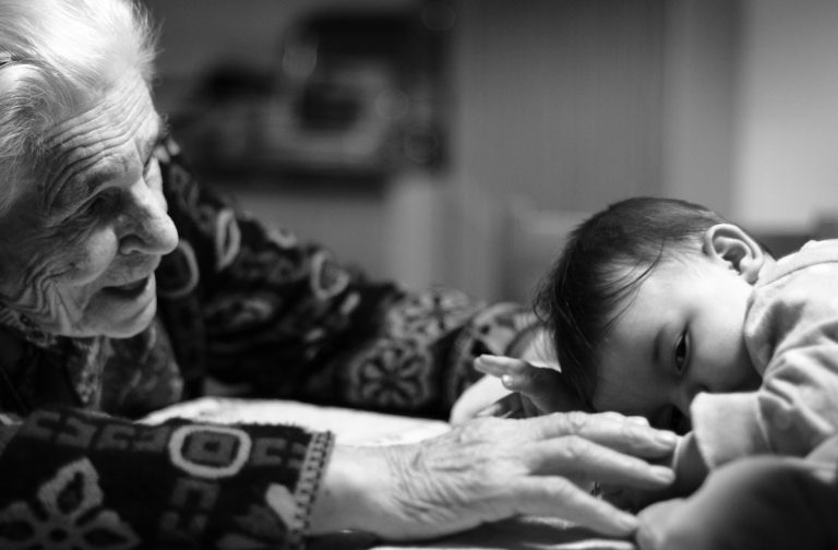 nonna allunga le braccia verso la nipotina neonata: i nonni nelle costellazioni familiari spesso rappresentano la salvezza per i nipoti
