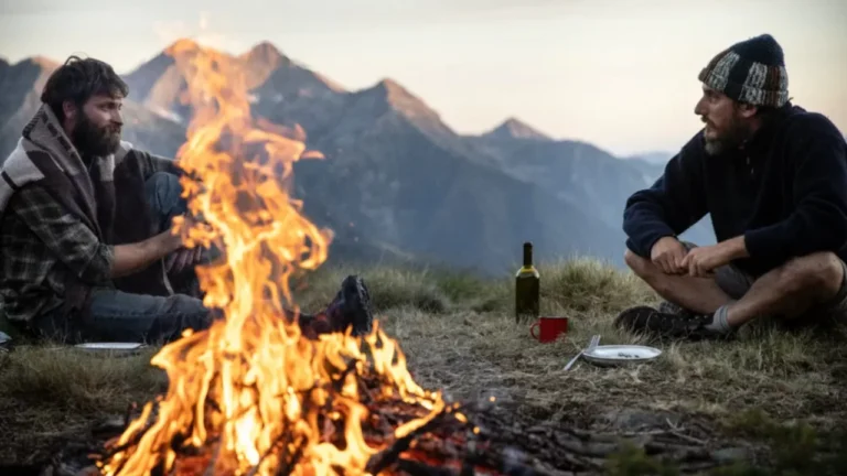una scena del film le otto montagne: Bruno e Pietro adulti di fronte a un fuoco