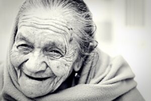 viso di donna anziana che sorride: epigenetica e costellazioni familiari indicano la felicità come condizione necessaria alla vita