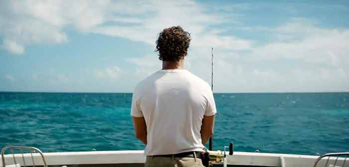uomo pesca su una barca di spalle: il film l'isola dell'inganno mostra com'è vivere in un videogioco
