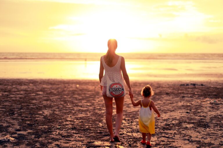 una mamma e sua figlia si tengono per mano camminando verso il tramonto. Il mal di schiena spesso è dovuto al giudizio verso i genitori, mentre la difficoltà a rimanere incinta da una mancanza di ordine nella famiglia
