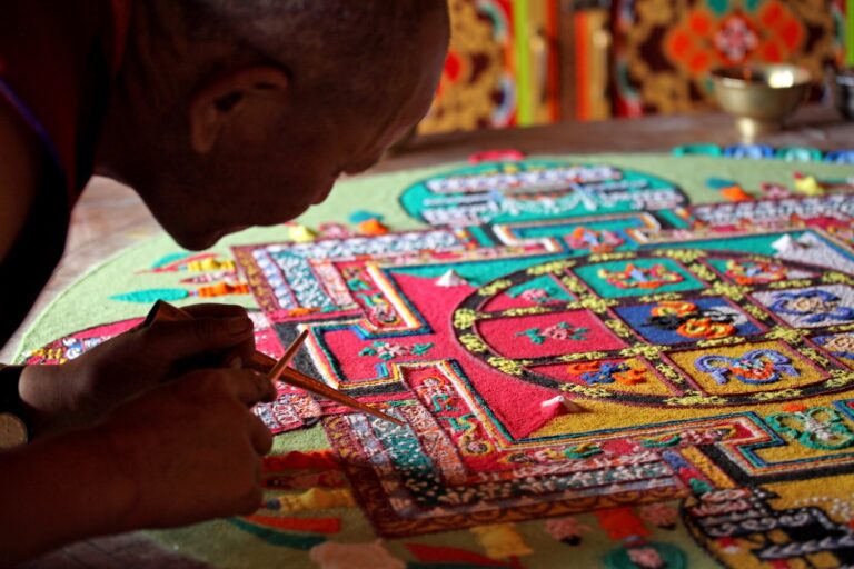 monaco tibetano esegue un mandala di Sabbia. Questa forma d'arte celebra l'impermanenza della vita