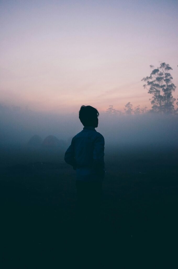una donna di spalle nella nebbia la sera