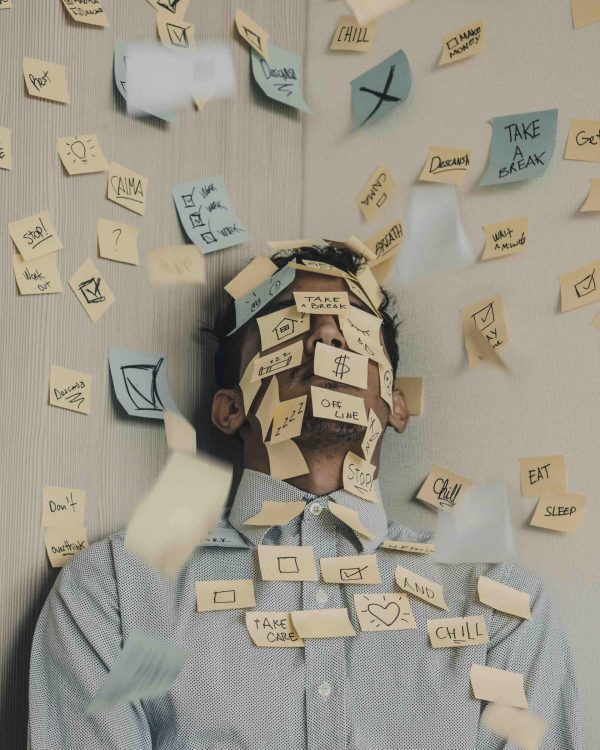 uomo coperto di post it con scritto sopra vari tipi di problemi