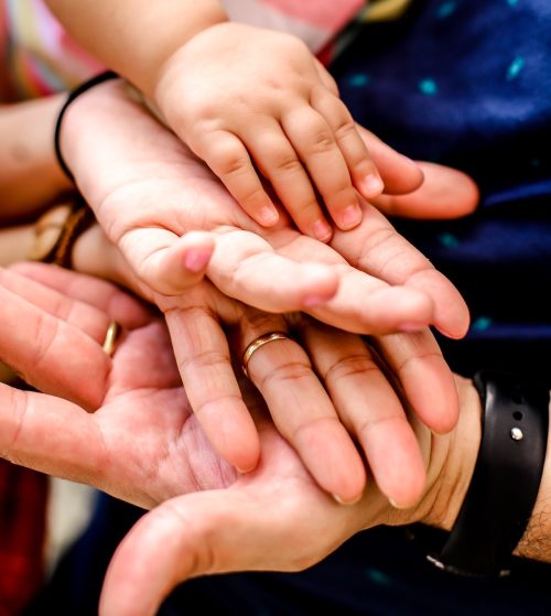 mano di una bambina appoggiata sopra le mani della mamma e della nonna