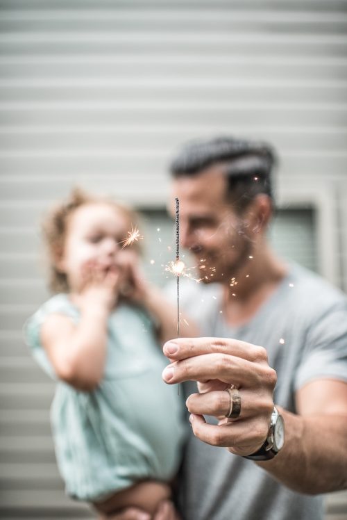 papà tiene in braccio la piccola figlia con una stellina a scintille in mano: la perversione spesso nasce dal volere essere come i genitori