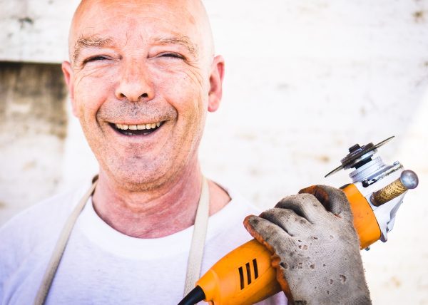 un operaio sorridente con in mano un flessibile: grazie alla ritrovata consapevolezza di volere essere felici al lavoro è crollato il mito del posto fisso