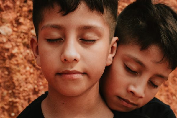 due bambini gemelli a occhi chiusi: uno sta davanti e uno si appoggia a lui dietro. La sindrome del gemello scomparso ci indica la drammaticità della separazione di due gemelli