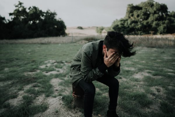 un uomo piange con le mani sul viso inginocchiato. sensibilità e fragilità spesso vengono confuse