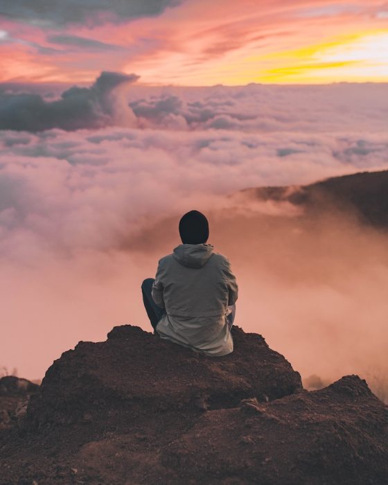 uomo siede in presenza in montagna meditando