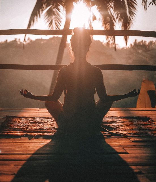 donna medita in posizione del loto al tramonto: cadere dall'ego all'ego spirituale è molto facile