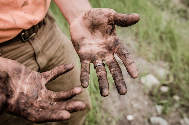 mani sporche di una persona che lavora la terra. Sembra chiedersi: tu preferisci sapere o essere?
