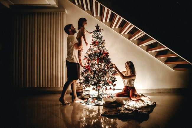 madre, padre e figlia preparano l'albero di Natale. Il perché si odia il Natale spesso è dovuto alla mancanza di un genitore
