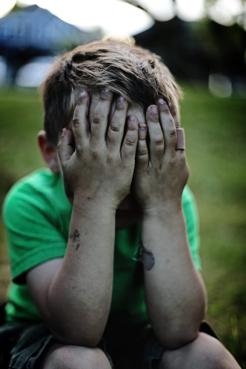 bambino piange con le mani sul viso: il dolore per un membro della famiglia genera l'irretimento che può essere visto insieme alle difficoltà della vita nelle costellazioni familiari