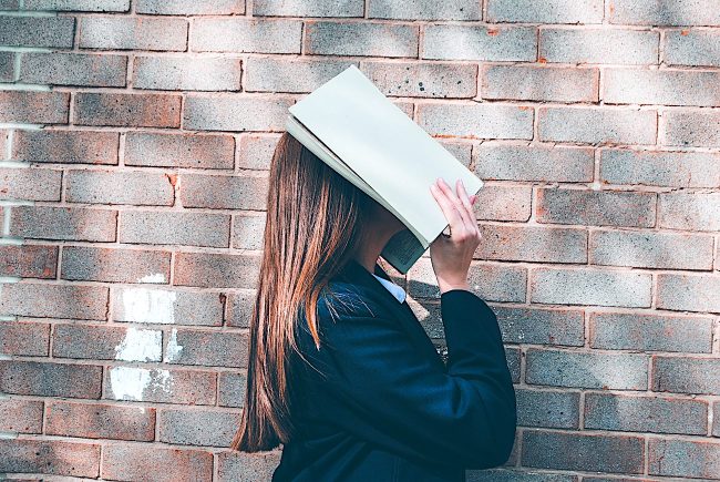 ragazza legge un libro camminando. Chiede a sé stessa: preferisci sapere o essere?