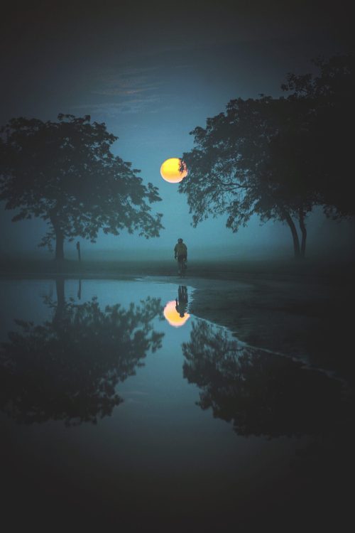 la luna si specchia in un lago con una figura umana sullo sfondo. Percepire è come riflettere la luce
