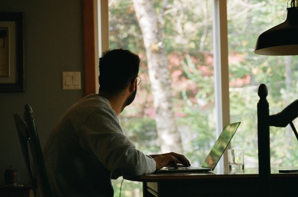 uomo lavora in casa sul pc guardando fuori dalla finestra: cosa è successo nel 2020 nel mondo del lavoro